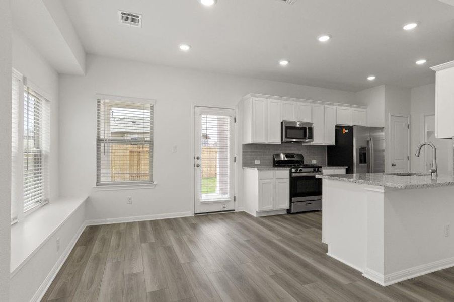 Kitchen featuring white cabinetry, stainless steel appliances, light stone counters, healthy amount of natural light, and recessed lighting Kitchen featuring white cabinetry, stainless steel appliances, light stone counters, healthy amount of natural light, and recessed lighting