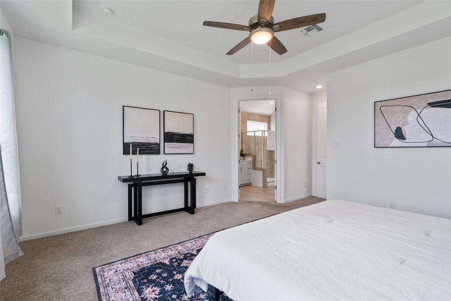A well-lit primary bedroom offers plush carpeting and a convenient en-suite bathroom access.