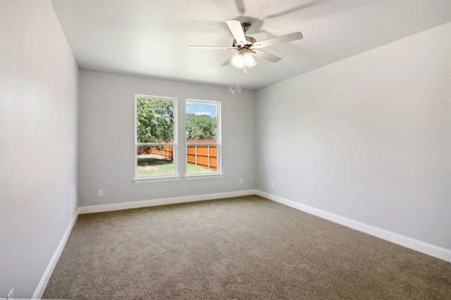 Carpeted empty room featuring ceiling fan