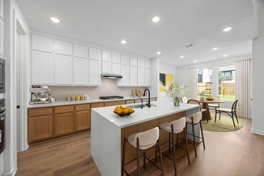 Kitchen featuring a kitchen bar, light wood finished floors, decorative backsplash, recessed lighting, and white cabinets Kitchen featuring a kitchen bar, light wood finished floors, decorative backsplash, recessed lighting, and white cabinets