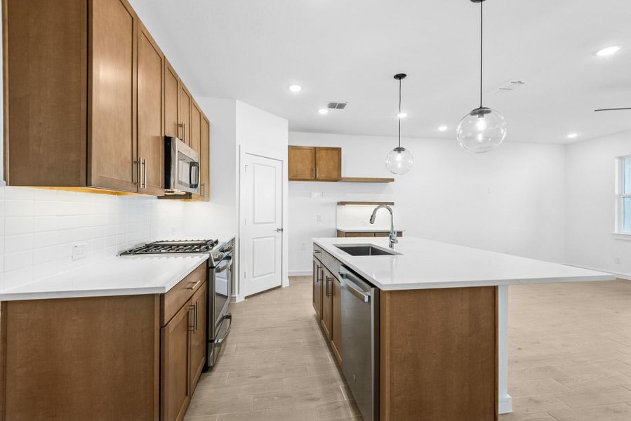 Stylish kitchen with light stain cabinets and quartz counters