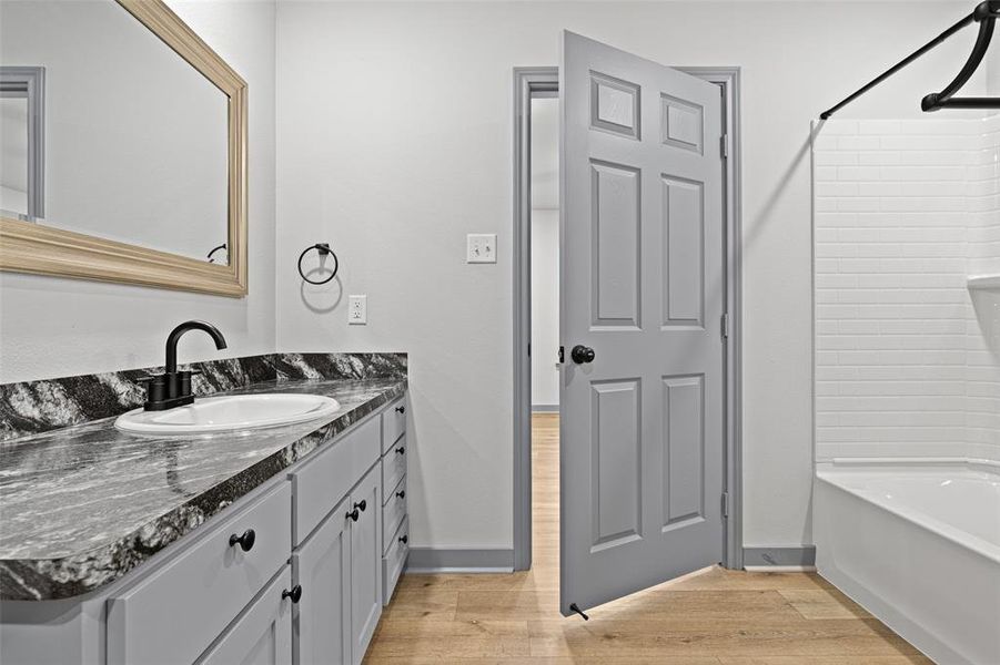 Bathroom with light wood-type flooring, vanity, and shower / tub combination Bathroom with light wood-type flooring, vanity, and shower / tub combination