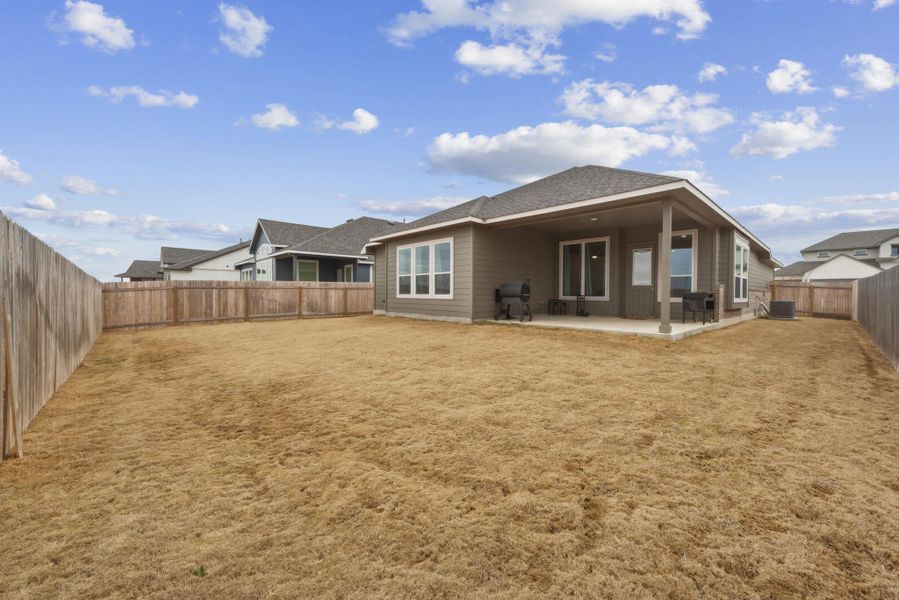 Rear view of house with a fenced backyard and a patio area