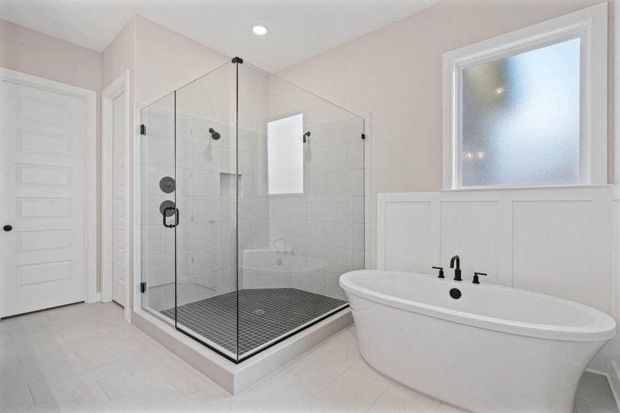 Full bath with a shower stall, a freestanding bath, healthy amount of natural light, and light tile patterned floors