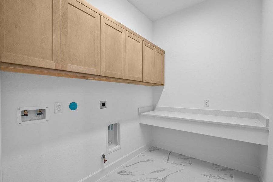 REPRESENTATIVE PHOTO: Laundry area has upper cabinets and a folding table