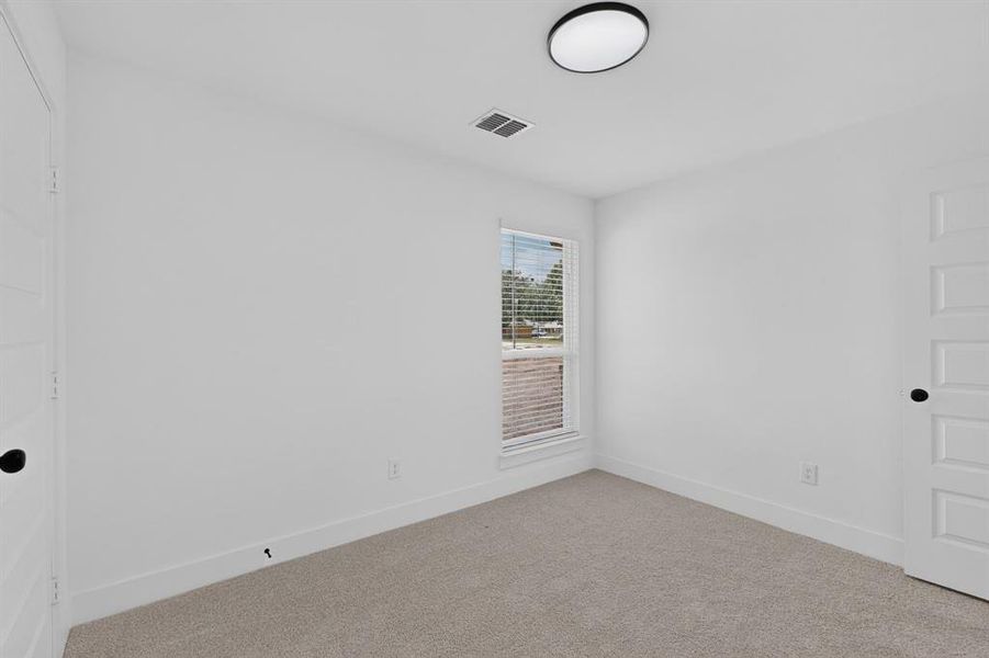 Bright room featuring a window with blinds, neutral carpet flooring, white walls, and a contemporary flush-mount ceiling light