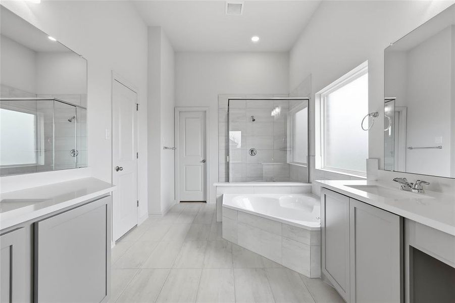 Bathroom featuring two vanities, a shower stall, a bath, and a closet