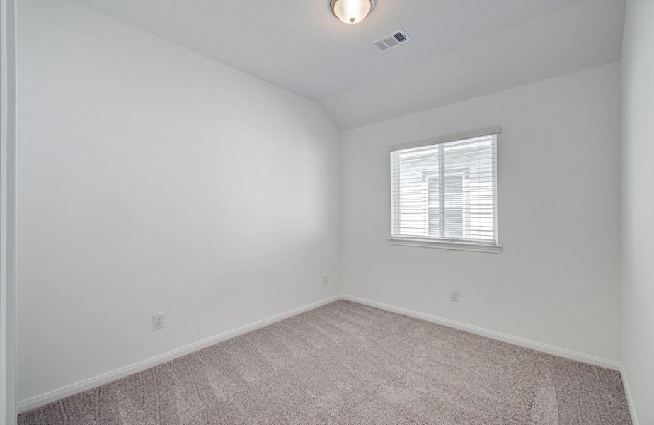 Bright and airy room with soft carpeting and a large window, ideal for a cozy bedroom or home office.