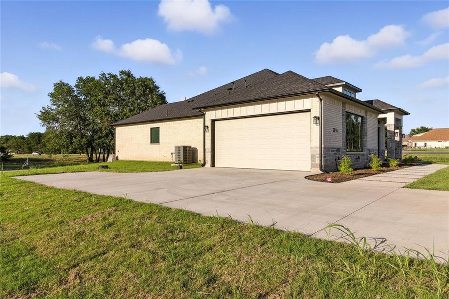 View of side of home with brick siding, a lawn, concrete driveway, a garage, and roof with shingles View of side of home with brick siding, a lawn, concrete driveway, a garage, and roof with shingles