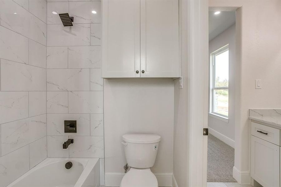 Toilet with storage and shower tub combo in Jack and Jill Bathroom.