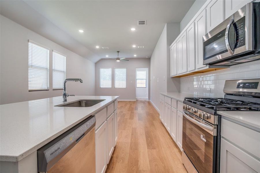 Kitchen with stainless steel appliances, recessed lighting, light wood-style floors, tasteful backsplash, and light stone countertops