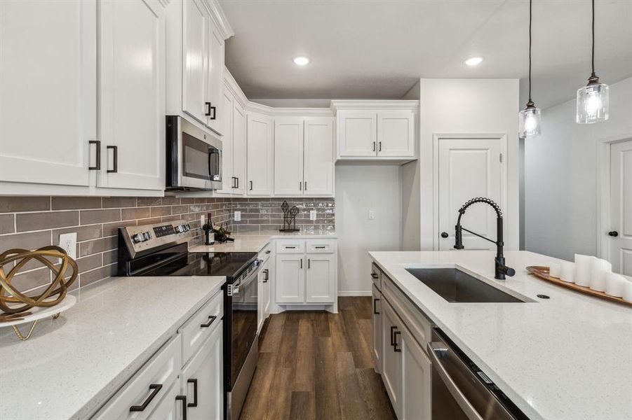 Kitchen with white cabinetry, dark hardwood / wood-style flooring, appliances with stainless steel finishes, decorative backsplash, and sink