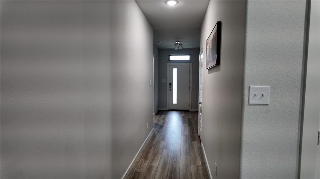 The property features a hallway with wood-style flooring and recessed lighting, leading to a front door with a vertical frosted glass insert and an overhead transom window