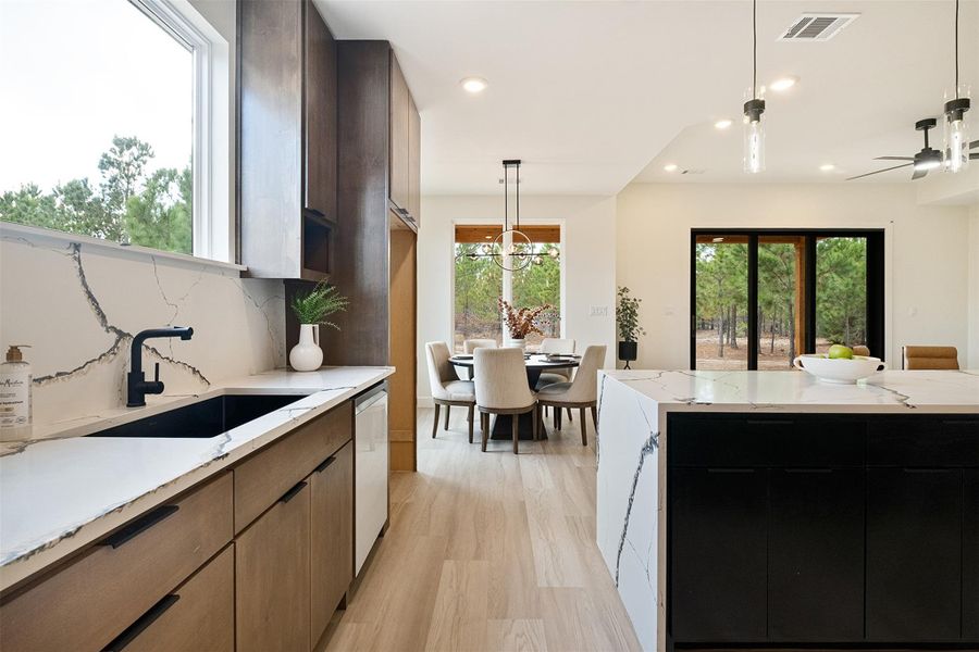 Kitchen featuring decorative backsplash, decorative light fixtures, light stone countertops, modern cabinets, and recessed lighting