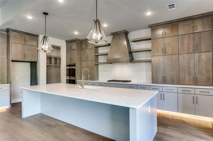 Kitchen featuring open shelves, backsplash, light wood finished floors, pendant lighting, and light stone countertops Kitchen featuring open shelves, backsplash, light wood finished floors, pendant lighting, and light stone countertops