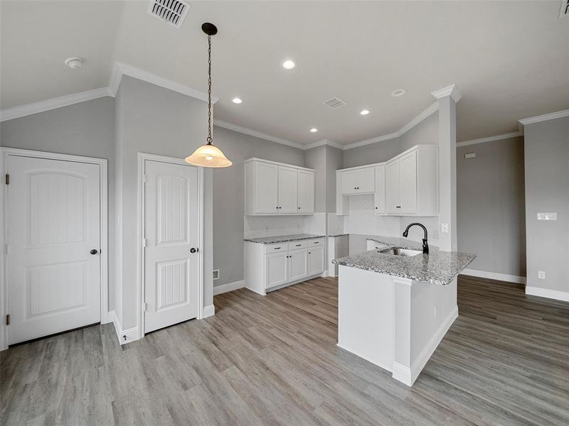 Kitchen with visible vents, light stone countertops, light wood-style flooring, white cabinetry, and a sink