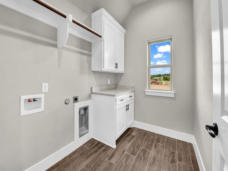Laundry room featuring wood tiled floors, gas dryer hookup, cabinet space, hookup for an electric dryer, and washer hookup Laundry room featuring wood tiled floors, gas dryer hookup, cabinet space, hookup for an electric dryer, and washer hookup