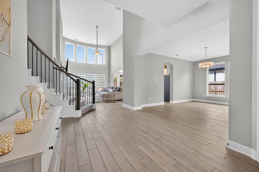 Elegant and expansive main living area with a dramatic curved staircase and panoramic window views. Seamless flow from dining to family room offers the perfect space for entertaining or everyday living.