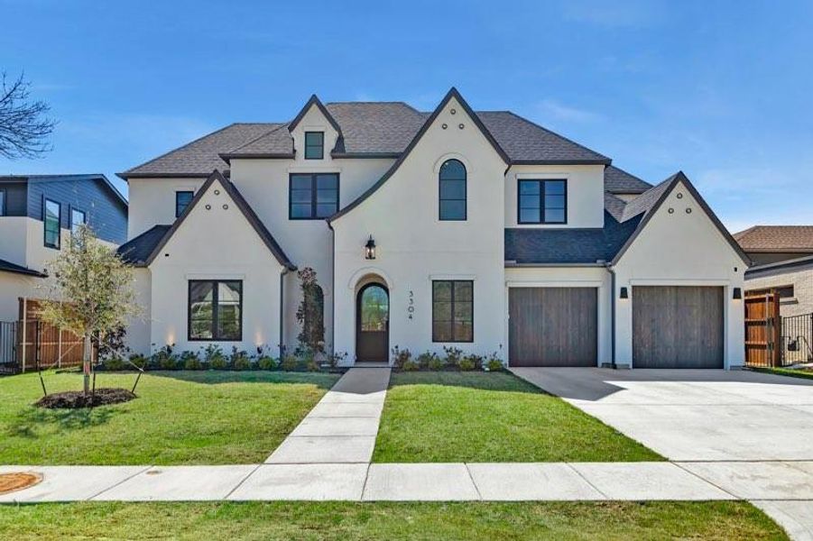 French country home with concrete driveway, stucco siding, and a shingled roof