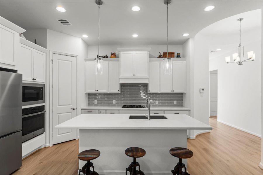 The rotunda entry leads to the light, bright kitchen with a generous island, white cabinets, gray subway tile and stainless appliances. A chef's dream!