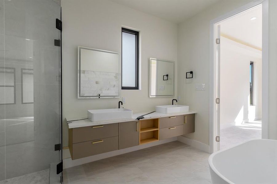 Bathroom featuring double vanity, a stall shower, a soaking tub, and light tile patterned flooring
