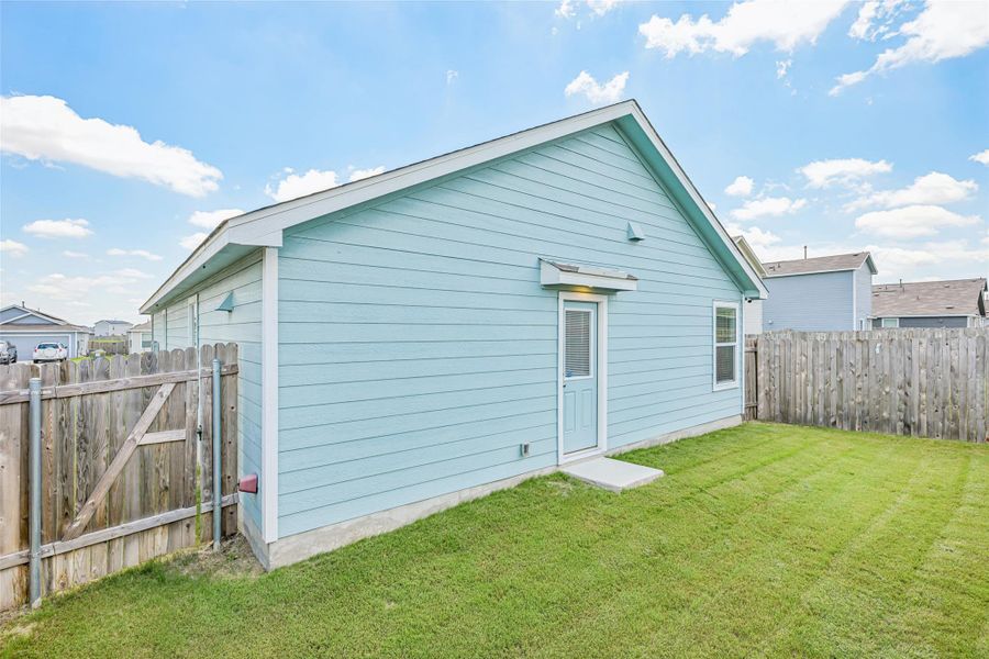 Exterior featuring light blue siding, a white trimmed gable roofline, a rear entry door, and a single pane window Exterior featuring light blue siding, a white trimmed gable roofline, a rear entry door, and a single pane window