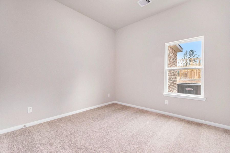 This room features neutral-toned walls and carpet, with a single window providing natural light and a view of the outside. It offers a simple, clean space ready for personalization.