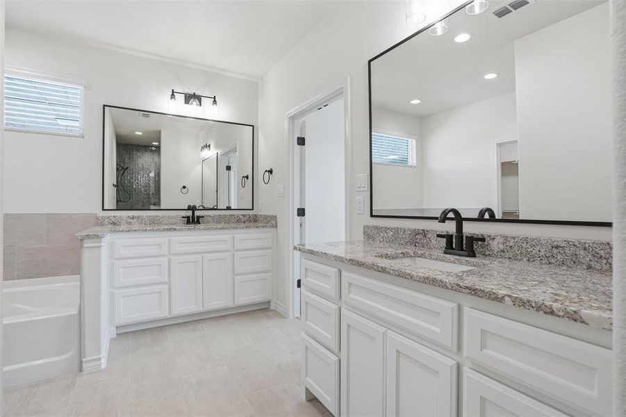 Bathroom featuring two vanities, healthy amount of natural light, a garden tub, and a shower stall Bathroom featuring two vanities, healthy amount of natural light, a garden tub, and a shower stall