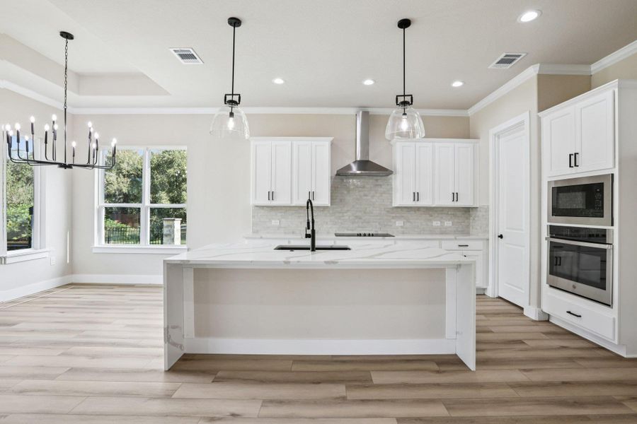 Kitchen featuring light stone counters, ornamental molding, oven, light wood-style floors, and white cabinets