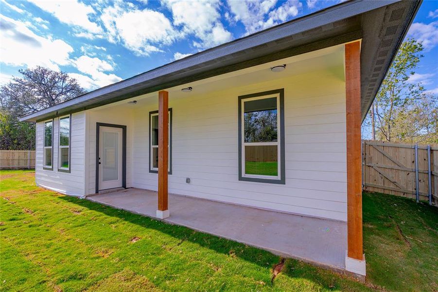 Rear view of property featuring a lawn and a patio