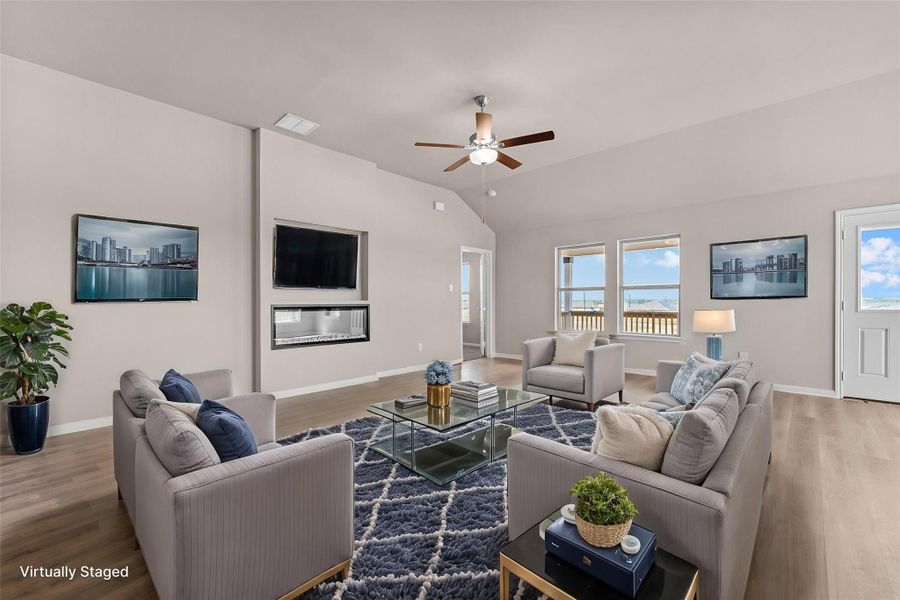 A contemporary living area features high ceilings, light wood flooring, and an elegant fireplace.