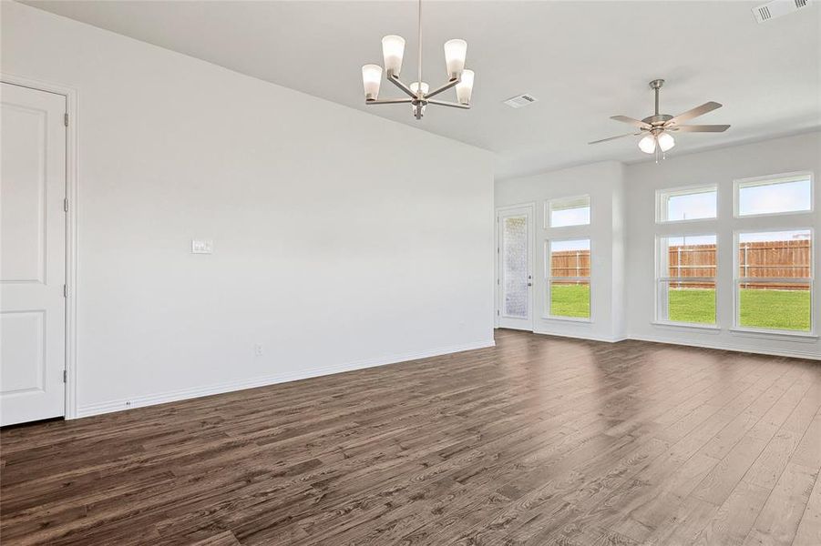 Unfurnished room featuring ceiling fan with notable chandelier and dark wood-type flooring