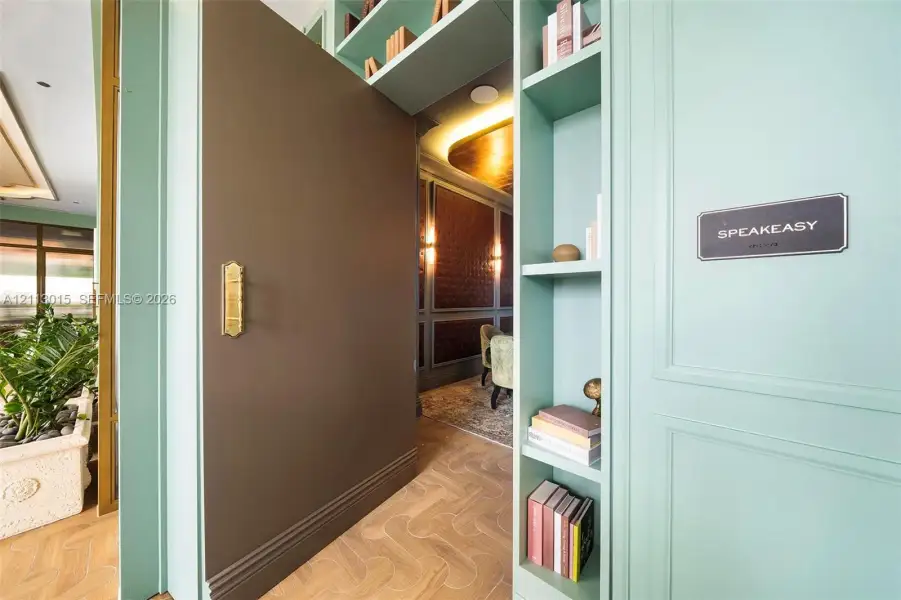 Pivot door with brass hardware, custom built-in cabinetry, herringbone-pattern wood flooring, and recessed ceiling lighting