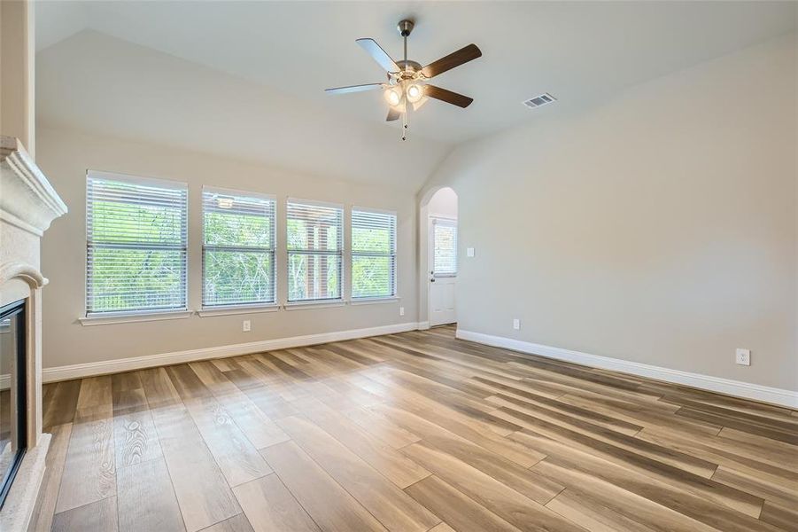 Unfurnished living room featuring light hardwood / wood-style flooring, ceiling fan, and high vaulted ceiling