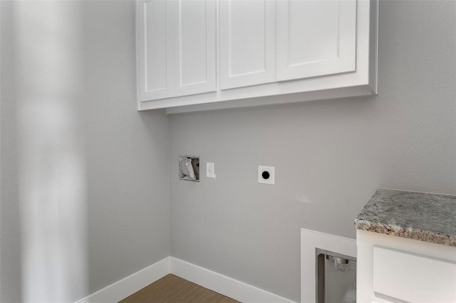 Clothes washing area with dark hardwood / wood-style flooring, cabinets, and hookup for an electric dryer