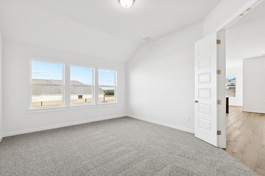 Empty room with lofted ceiling and light carpet Empty room with lofted ceiling and light carpet