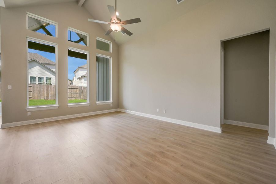 Empty room with light wood-type flooring, high vaulted ceiling, a ceiling fan, and beam ceiling