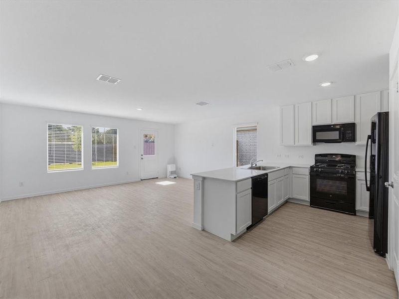 Open-concept living space featuring wood-finish flooring, recessed lighting, and white walls