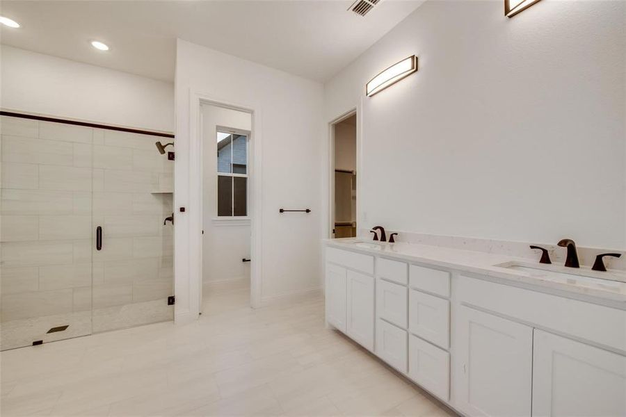 Bathroom with double vanity, a stall shower, and recessed lighting