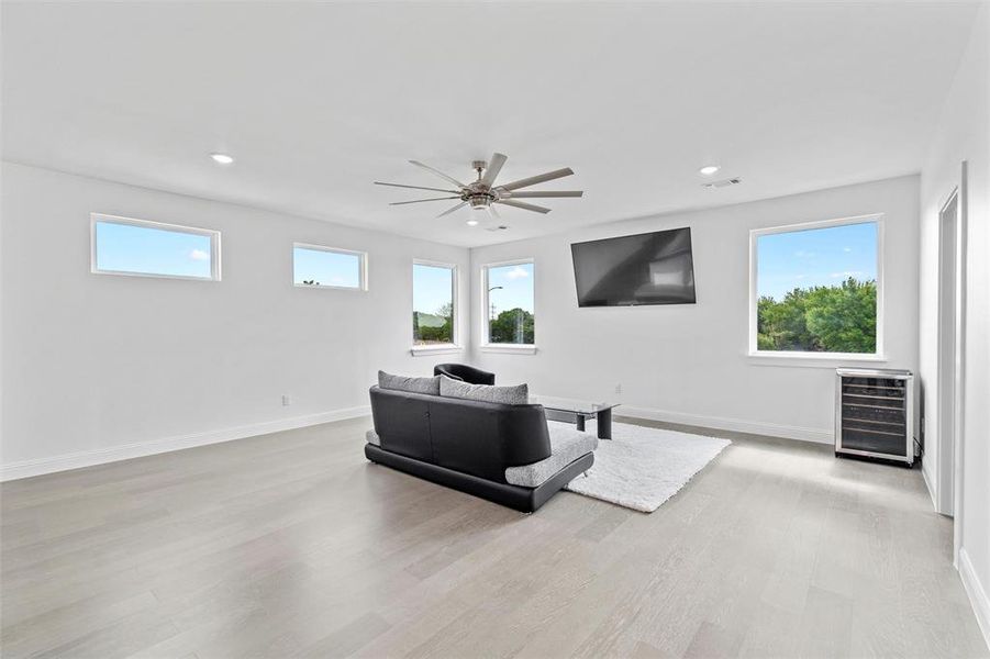 Living room featuring beverage cooler, ceiling fan, and light hardwood / wood-style flooring