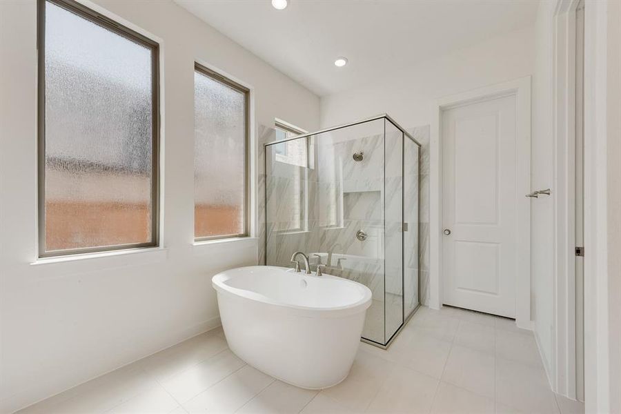 Full bathroom with a freestanding tub, a marble finish shower, light tile patterned floors, and recessed lighting Full bathroom with a freestanding tub, a marble finish shower, light tile patterned floors, and recessed lighting