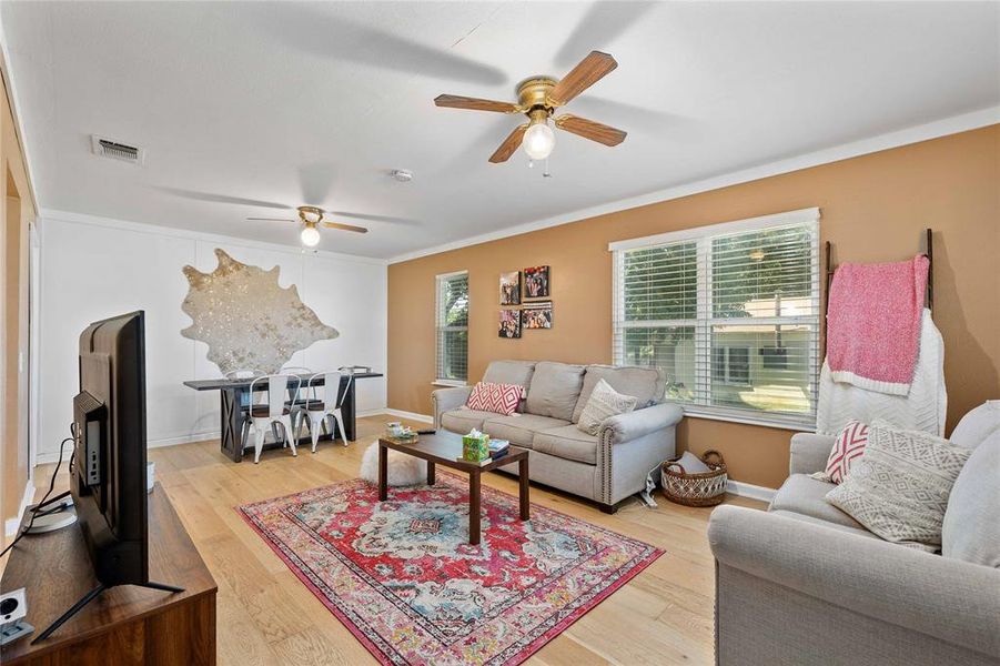 Living area with wood finished floors, ceiling fan, and crown molding Living area with wood finished floors, ceiling fan, and crown molding