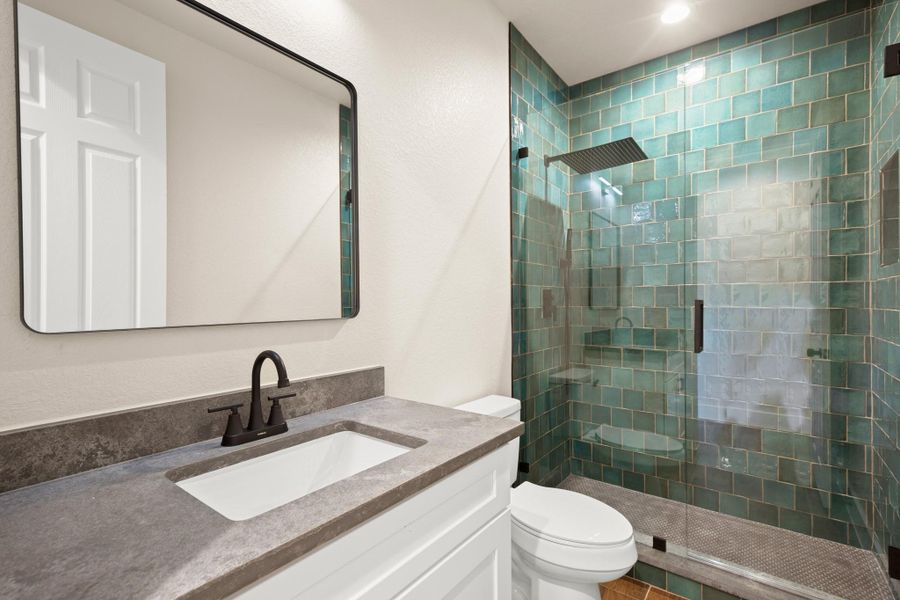 Full bath featuring a tile shower and vanity