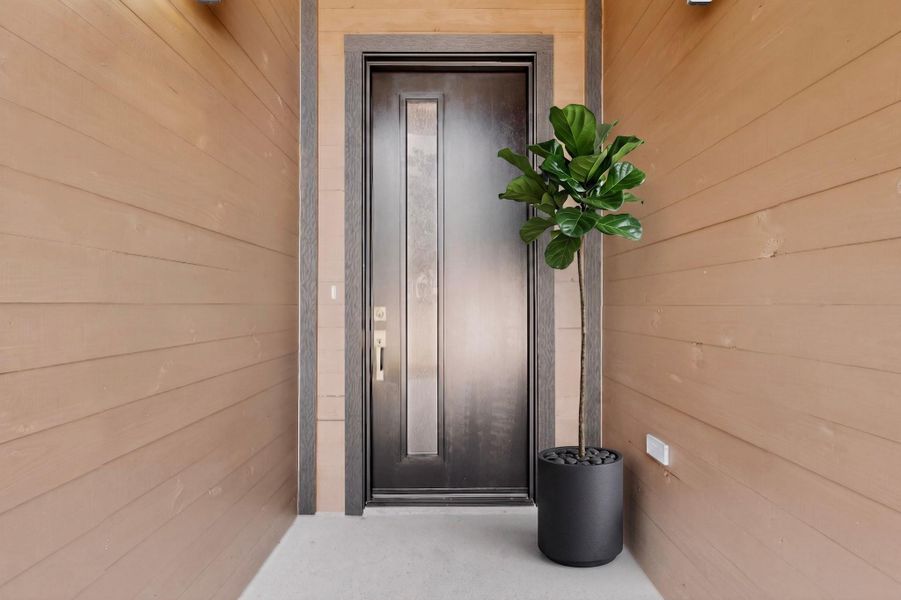 A welcoming entry features a sleek dark door framed by natural wood siding.