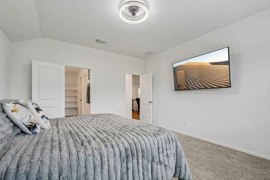 Carpeted bedroom with a walk in closet and lofted ceiling