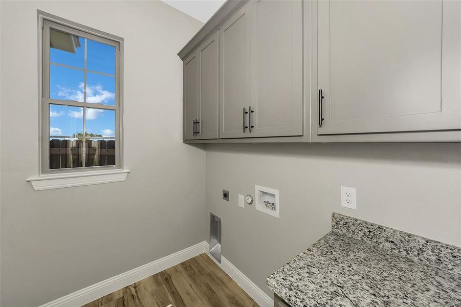 Laundry room with cabinet space, electric dryer hookup, wood finished floors, hookup for a washing machine, and gas dryer hookup