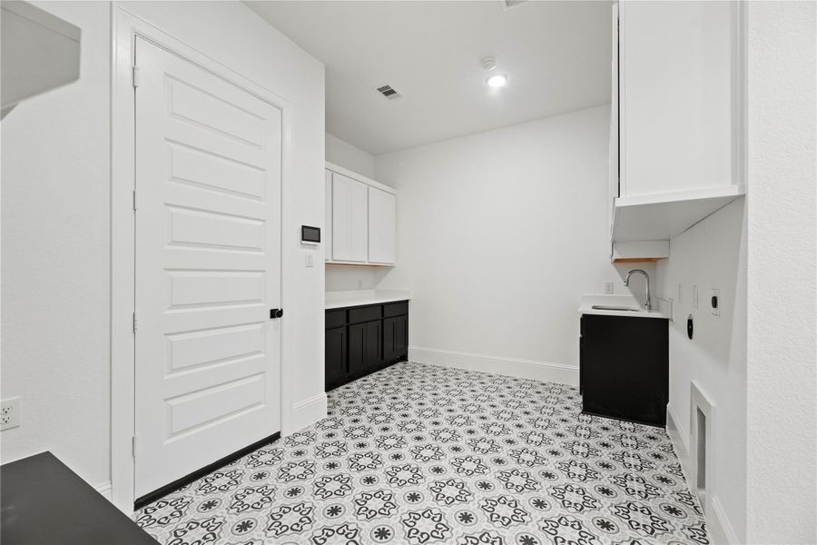 Spacious laundry room with abundant cabinetry and a built-in sink.