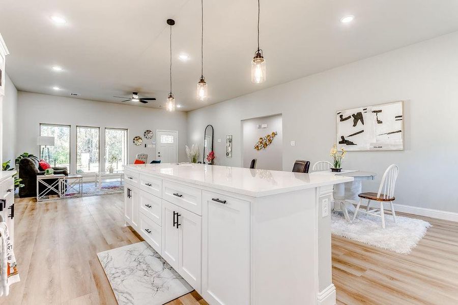 Kitchen with a center island, a kitchen breakfast bar, decorative light fixtures, light hardwood / wood-style floors, and white cabinetry