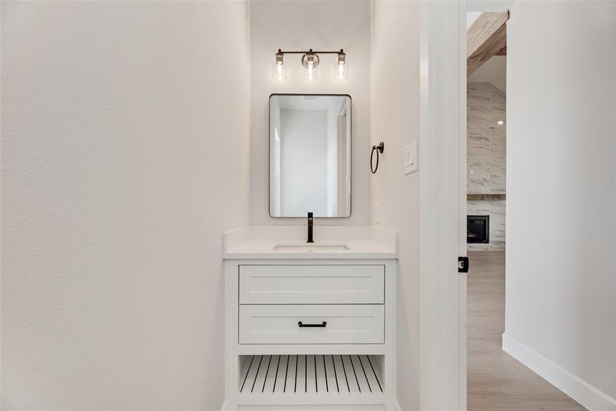 Bathroom with vanity, light wood-style floors, and a large fireplace