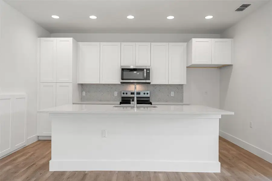 Kitchen with decorative backsplash, white cabinetry, appliances with stainless steel finishes, light stone countertops, and recessed lighting